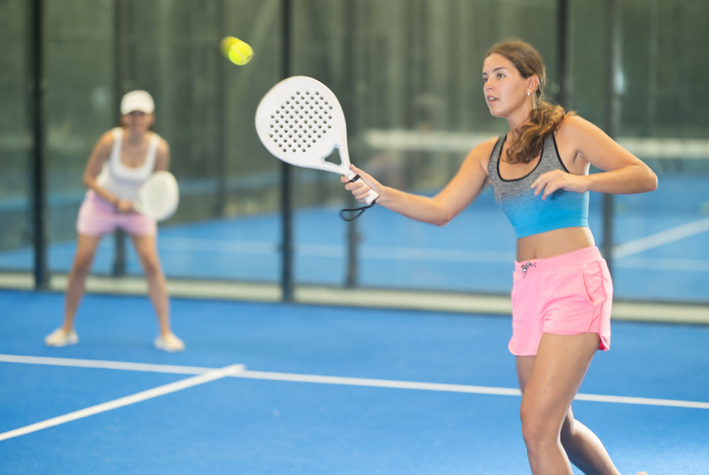 Young and adult women playing doubles tennis