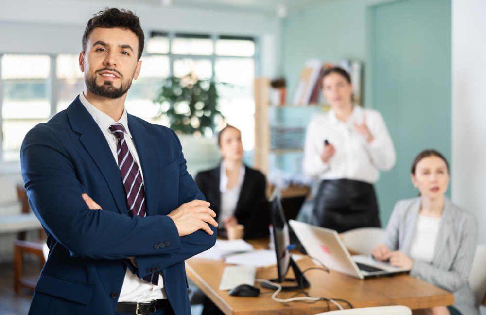 Male employee of the company stands against the background of a modern office