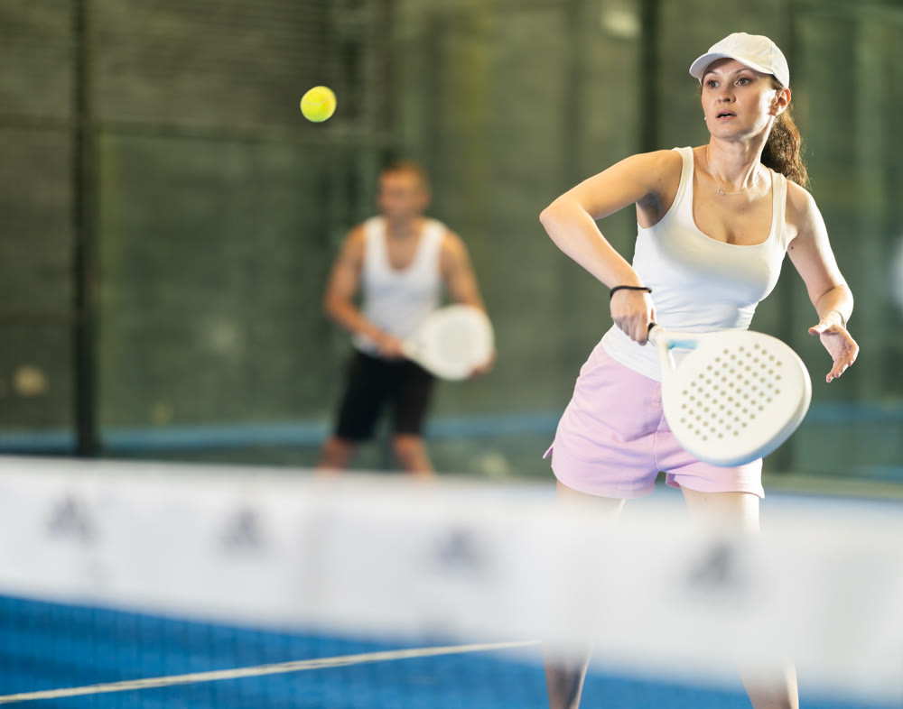 Young man and adult woman playing doubles tennis