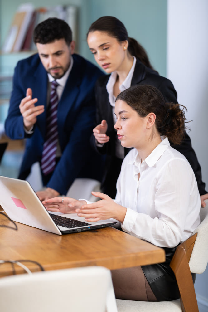 Group of qualified employees help a female intern work on a laptop