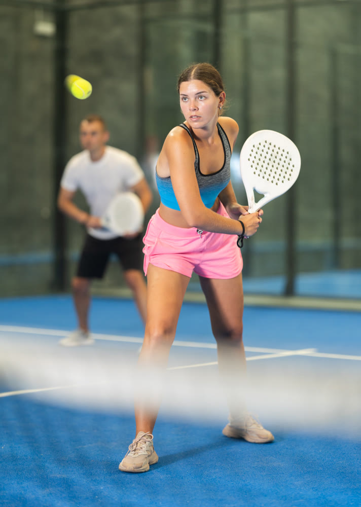 Young woman and man playing doubles tennis