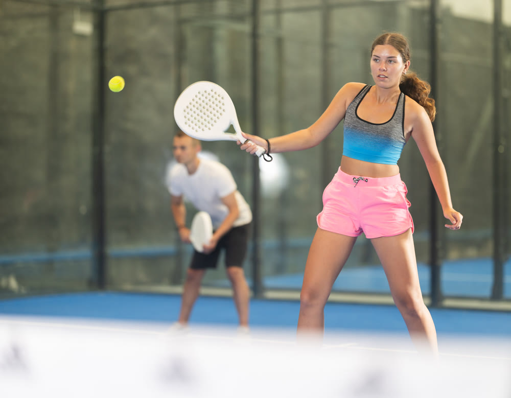 Padel game - girl with partners plays on tennis court