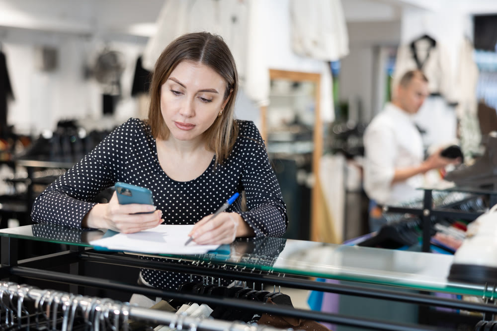 Young woman signing document in clothing store