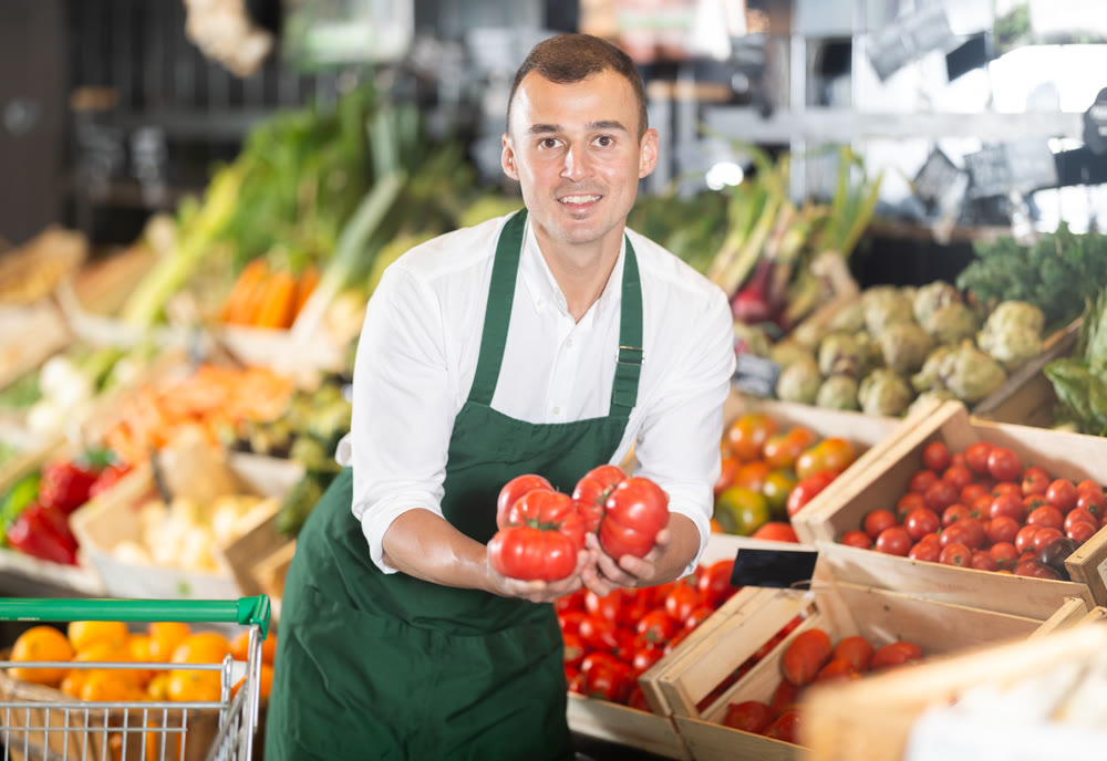 Friendly seller offering fresh tomatoes in organic grocery store