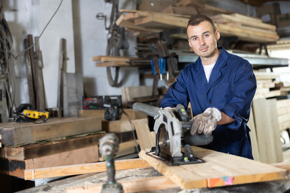 Young man saws oak plank in workshop