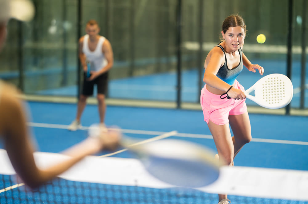 Young woman and man playing tennis against woman