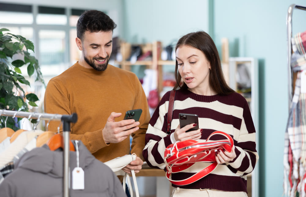 Woman pick out and scan QR code on handbag, man help to choose accessories