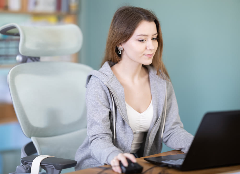 Young woman sitting at desk and working on laptop