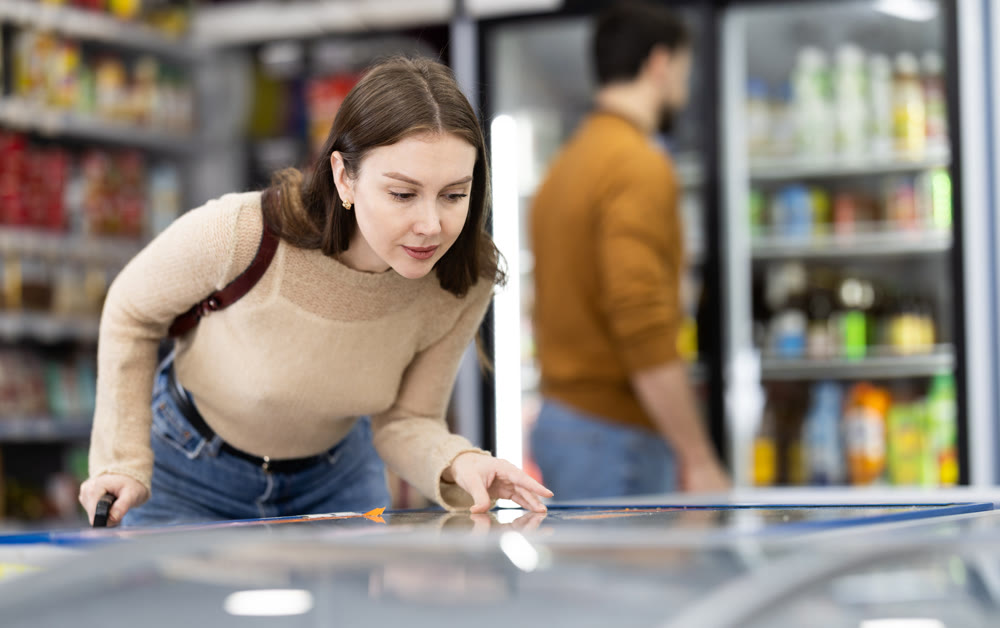 Young woman choosing frozen food in grocery store