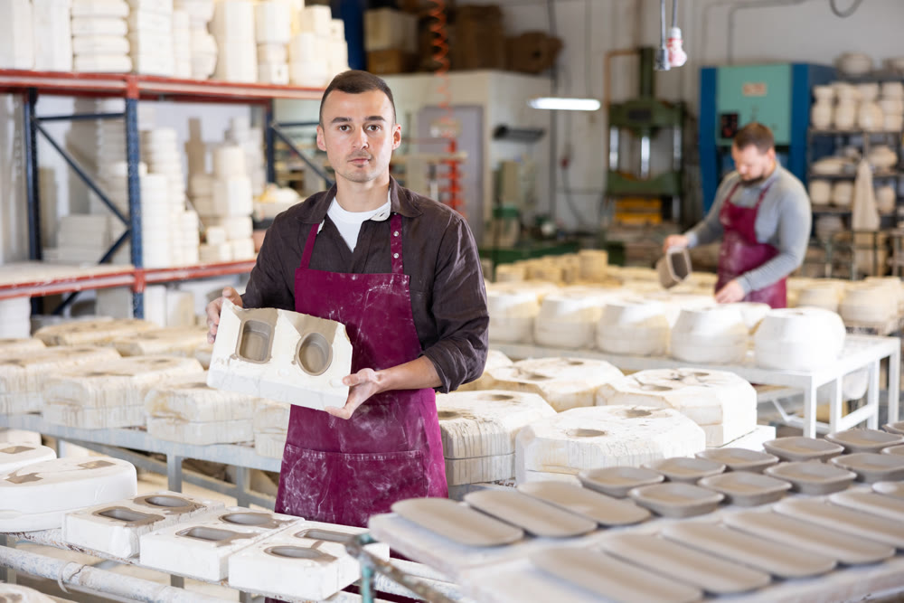 Young man showing poured clay molds