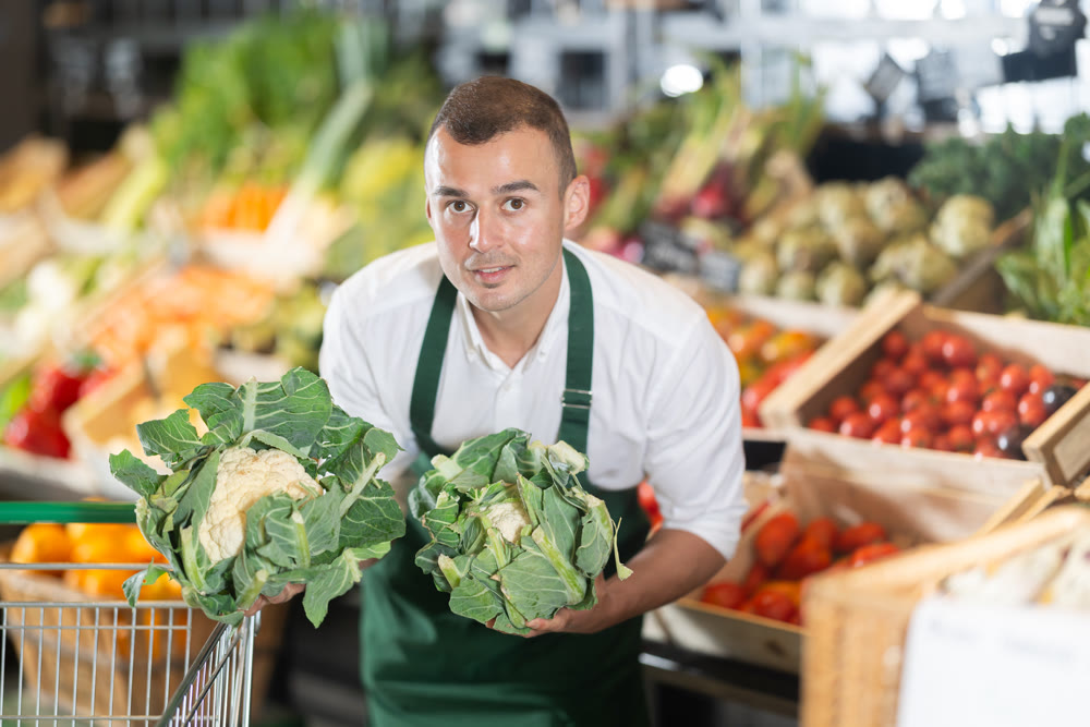 Vendor sorting fresh cauliflower on display in farm market