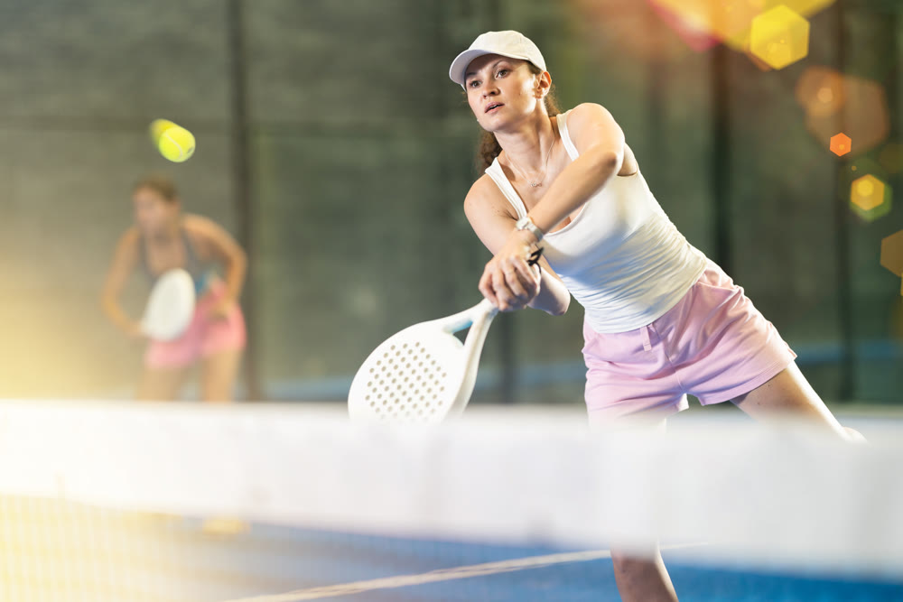 Young and adult women playing doubles tennis