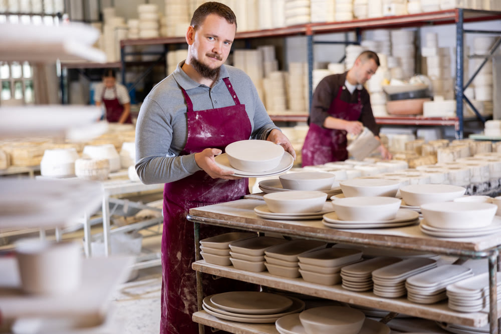 Ceramicist placing plates on storage racks in pottery studio