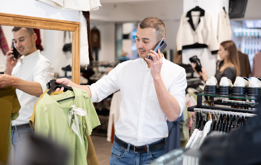 Young man chooses blouse and talks on phone