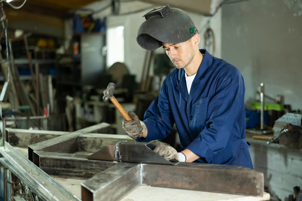 During manufacture of product, man employee works with welding machine