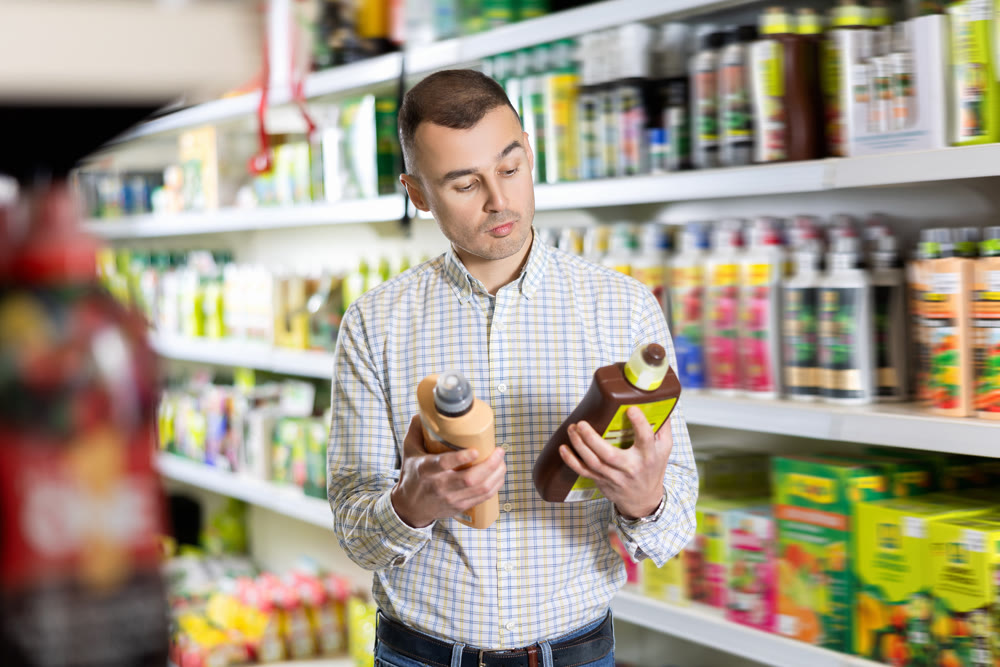 Male buyer shopping for fertilizer in hardware supermarket