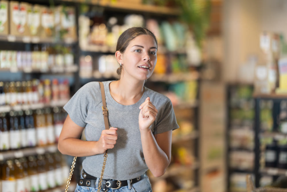 Young female shopper browsing grocery shelves at supermarket