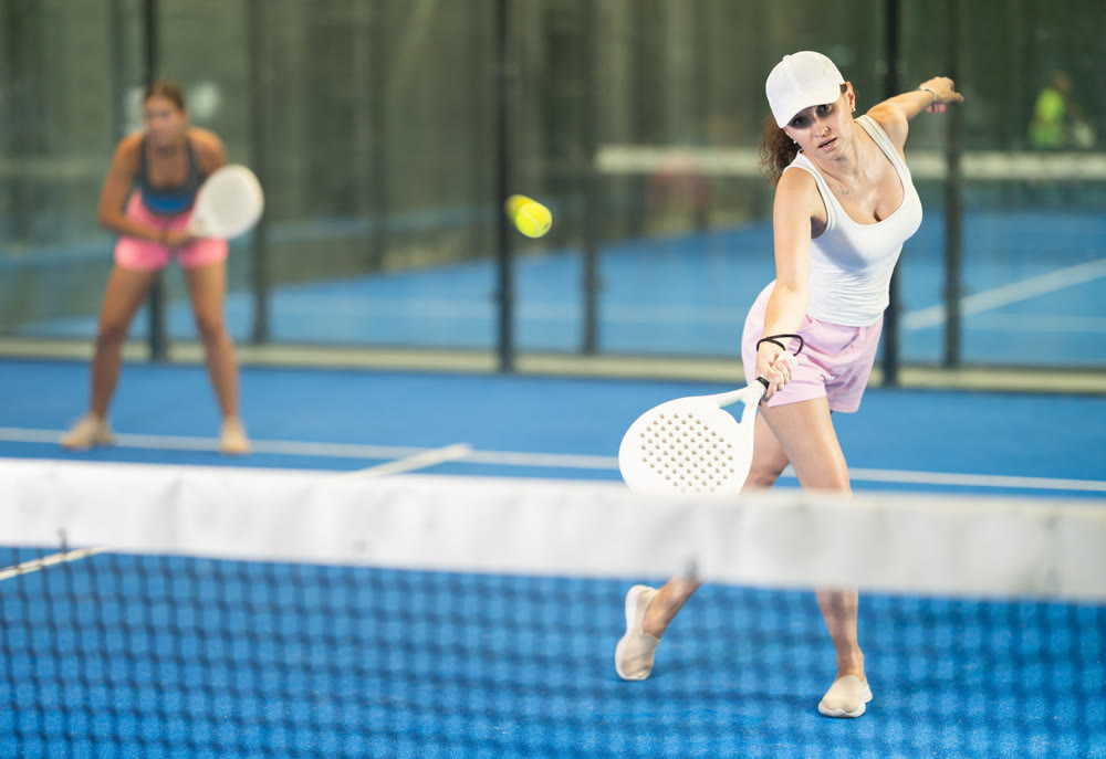 Young and adult women playing doubles tennis