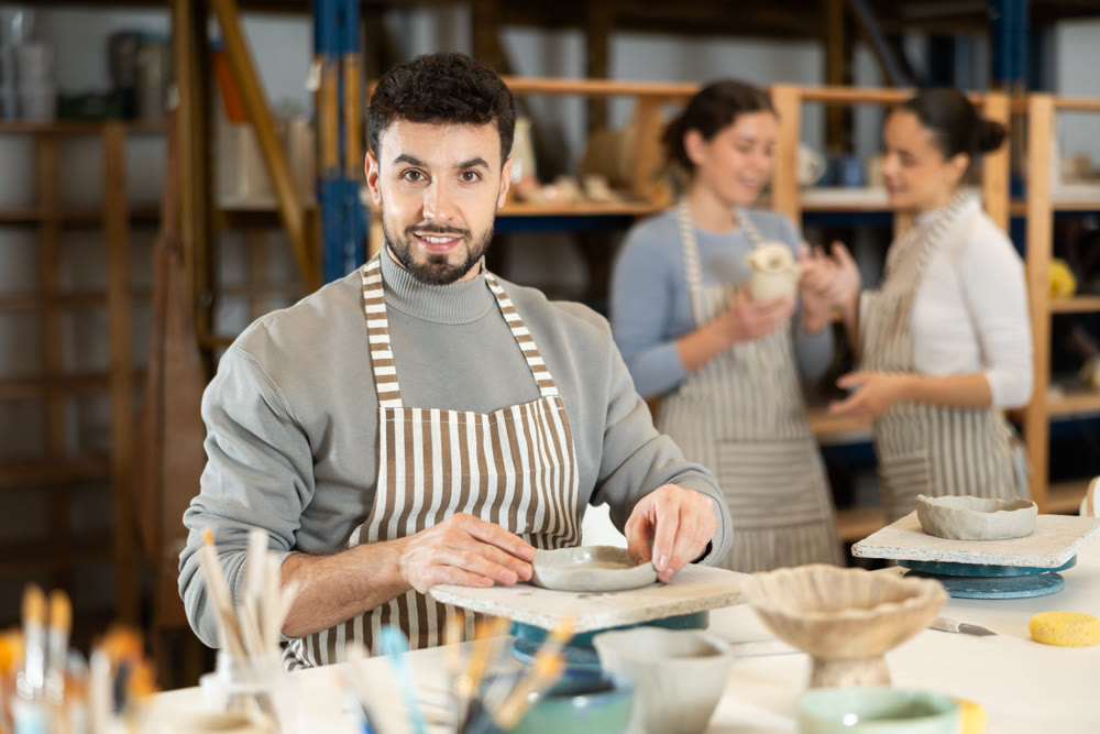 Guy sitting at table, busy making products from raw clay