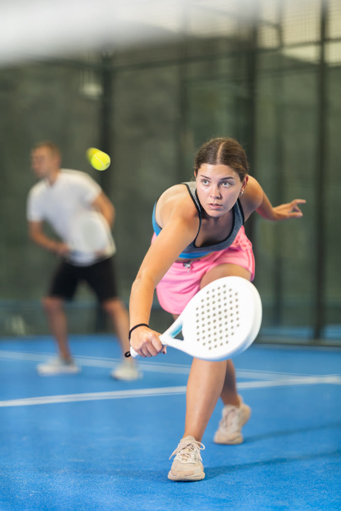 Young woman and man playing doubles tennis