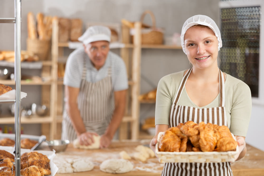 Bakery girl employee holds ready-made croissants.