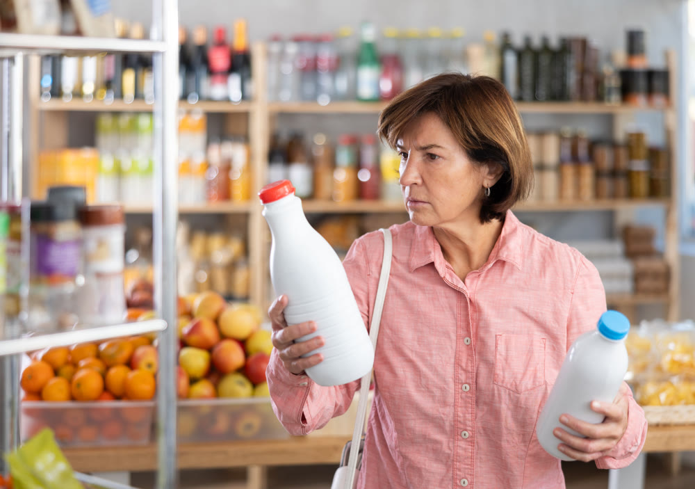 Mature woman choosing bottled milk in grocery store