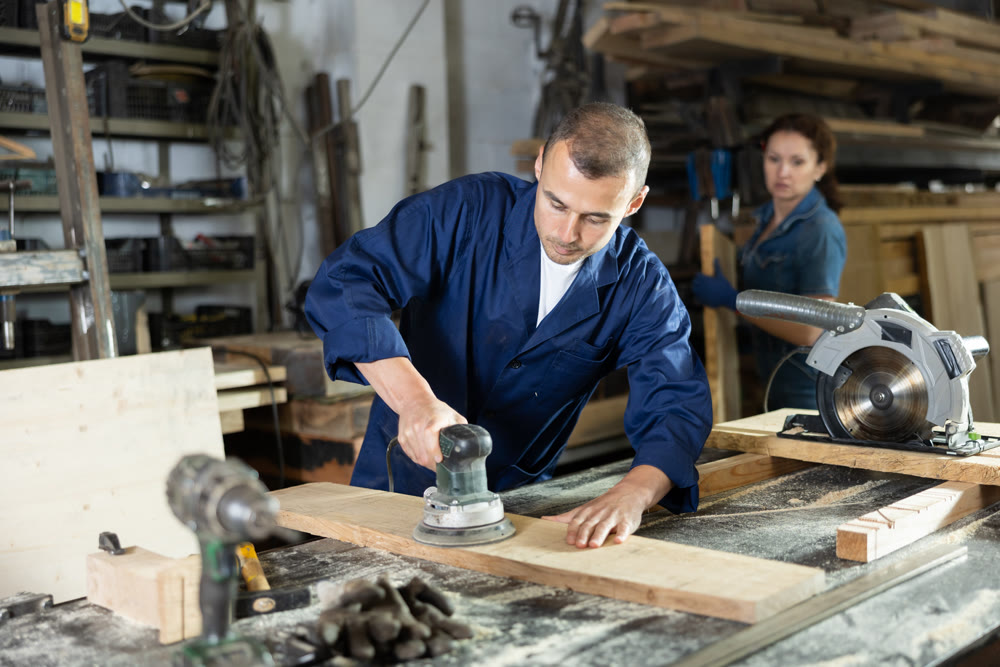 Man sanding a wooden board using sanding machine