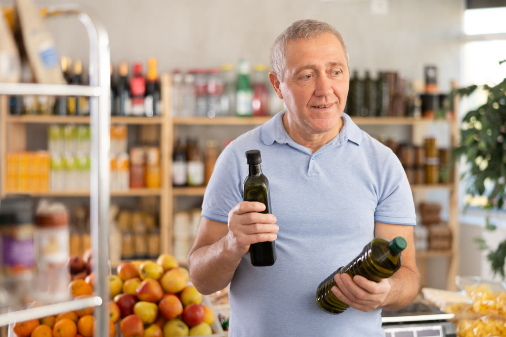 Mature man choosing olive oil in grocery store