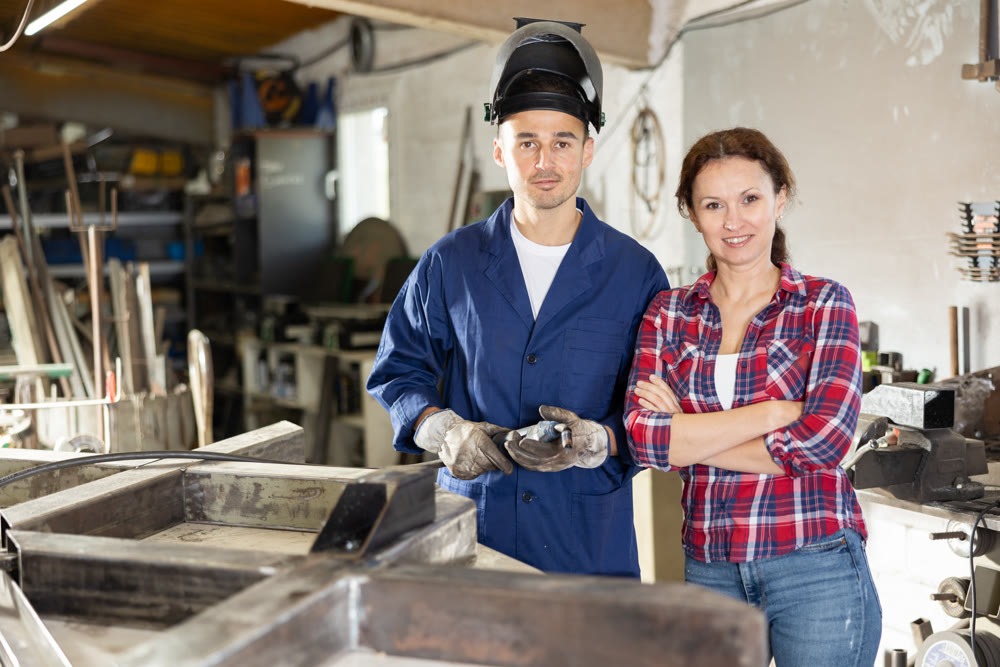 Portrait of male welder in protective mask and female manager of metal structures plant