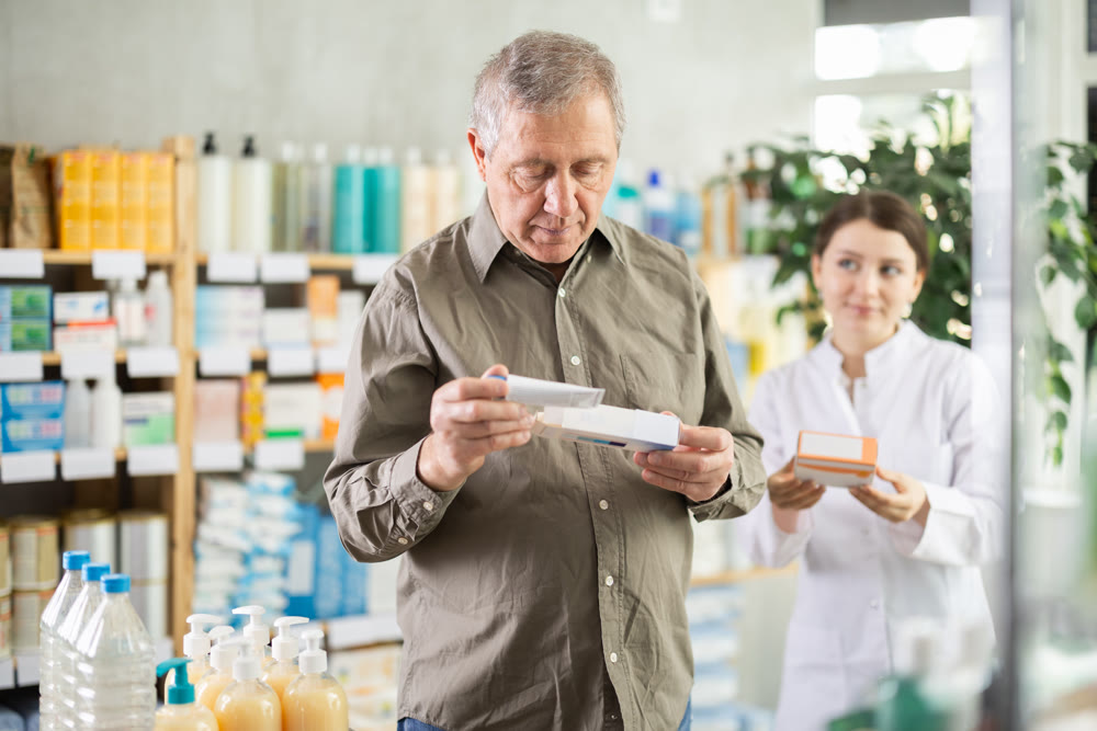 Man choosing ointment with help from pharmacist