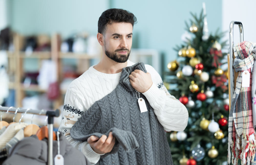 Young man chooses sweater in clothing store