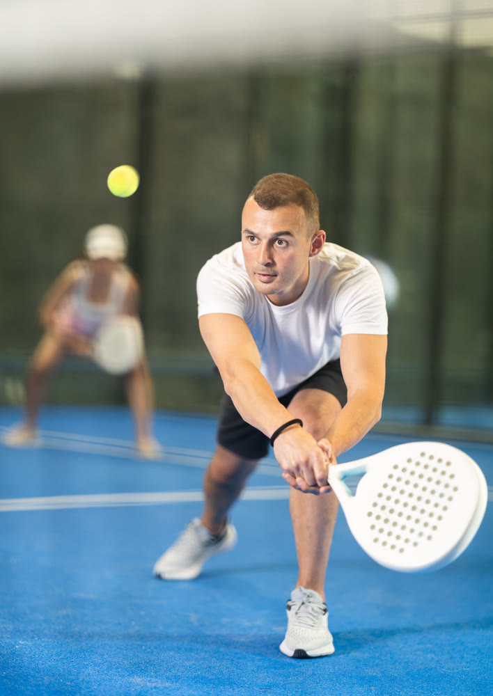 Young man and adult woman playing doubles tennis