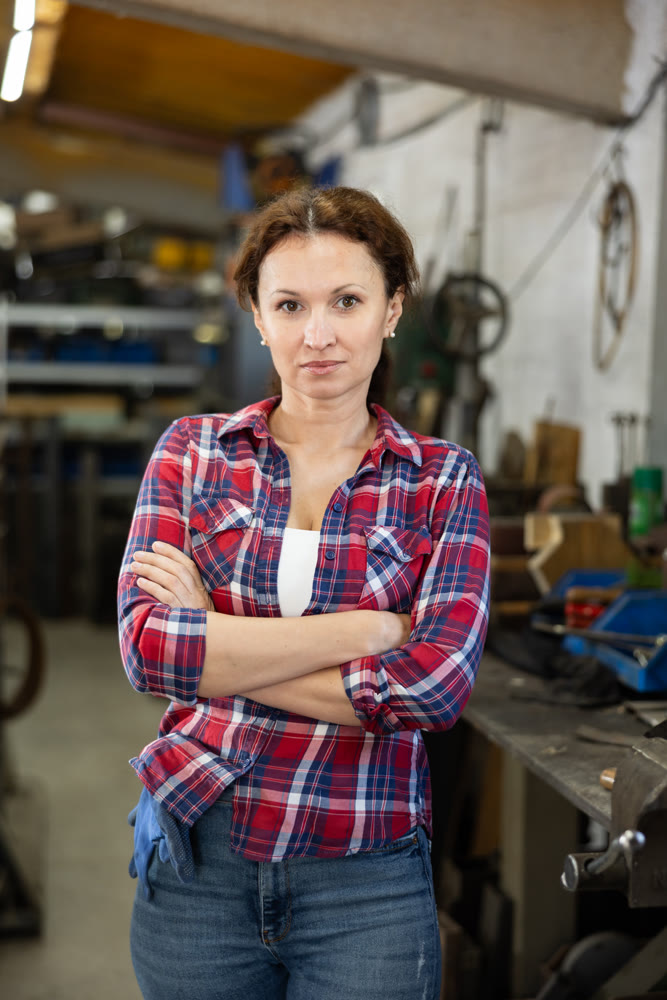 Portrait of confident female worker in workshop of metallurgical plant