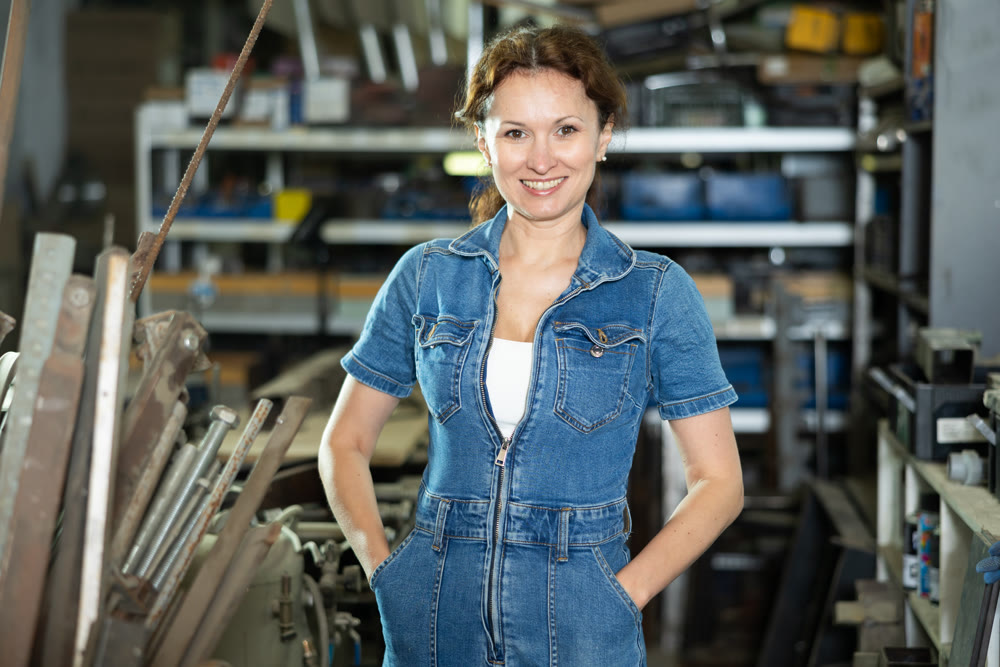 Woman employee of carpentry workshop took time out from work, stands resting