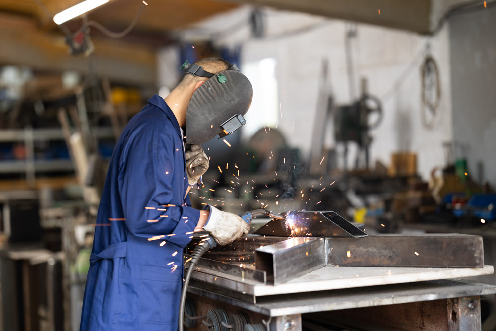During manufacture of product, man employee works with welding machine