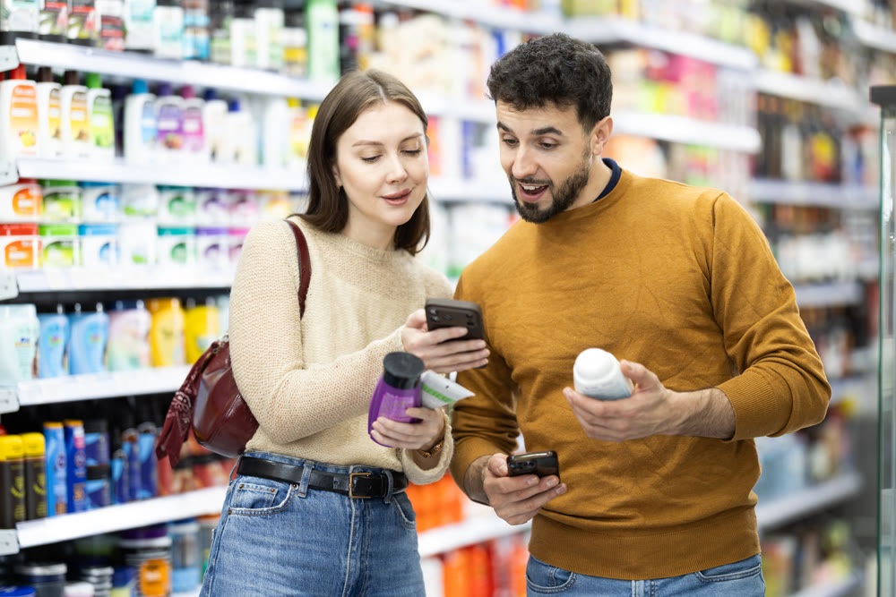 Married couple buyers scanning qr code for shampoo or shower gel in household chemicals store