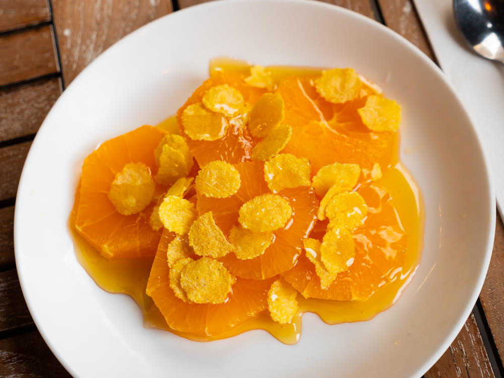 Orange slices drizzled with honey and sprinkled with corn flakes on plate