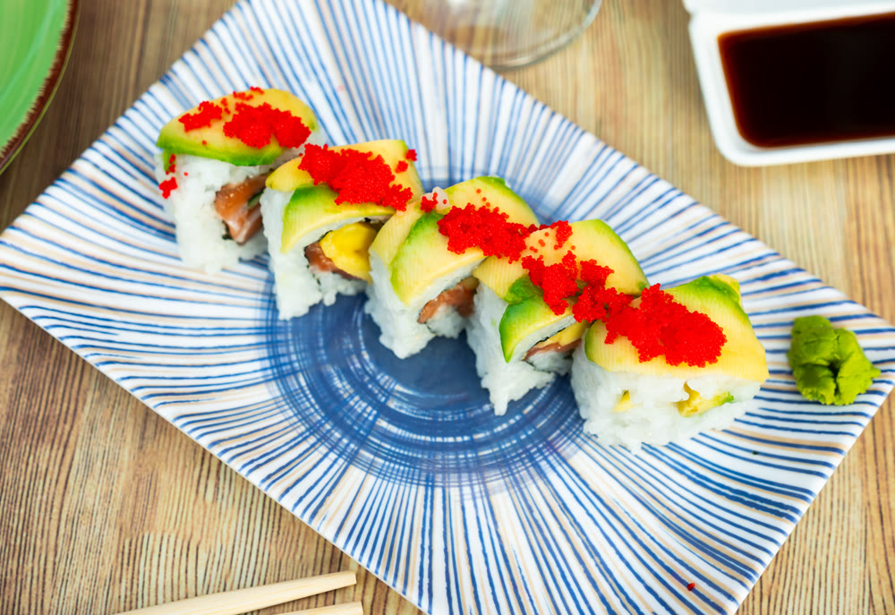 Uramaki - Dragon sushi roll with salmon and mango, tropical flavor.