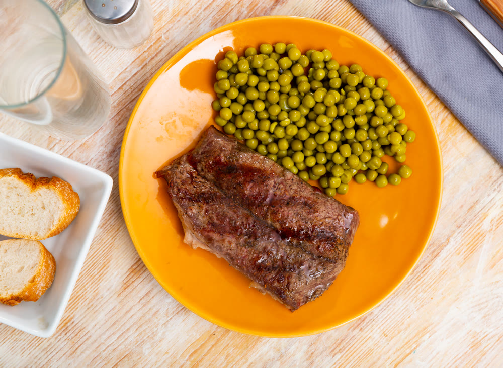 Popular all over the world dish of appetizing fried beef steak, subject with green peas