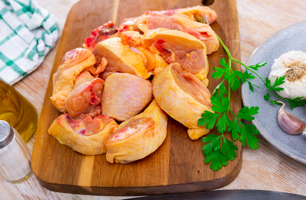 Raw sliced chicken on wooden cutting board