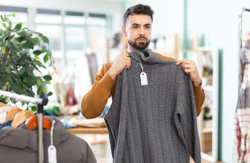 Young man choosing sweater in clothing store