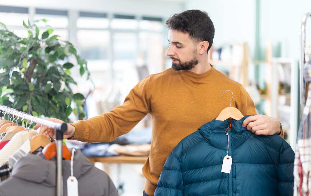 Man choosing a jacket of his size in a clothing store
