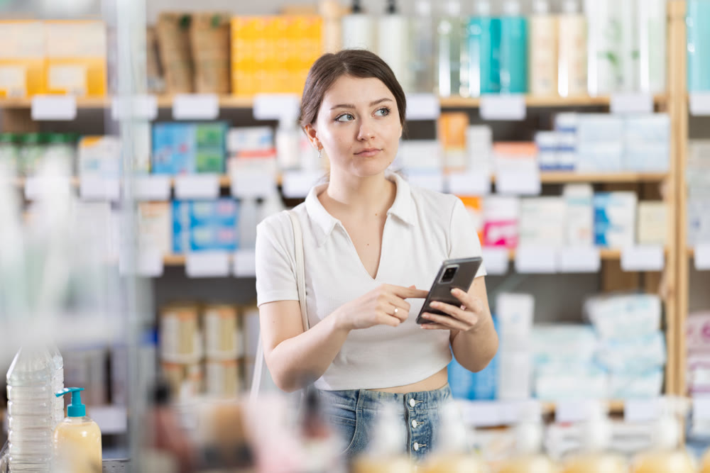 Woman standing in pharmacy with mobile phone