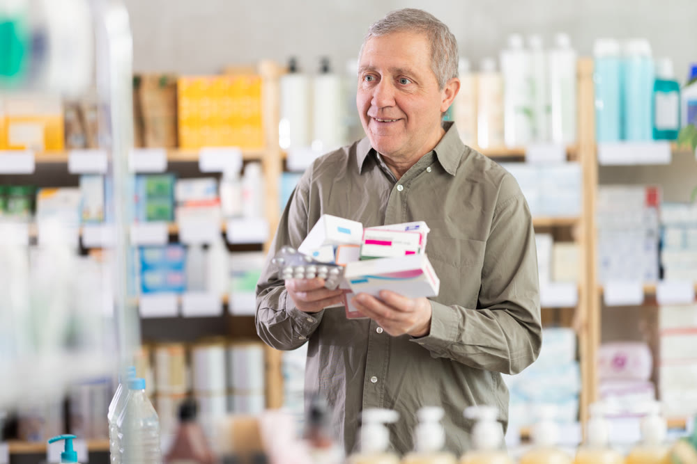Older man checking different medications in pharmacy