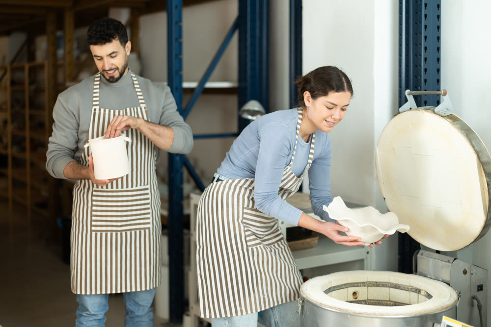Girl in apron put or takes clay vase out of oven