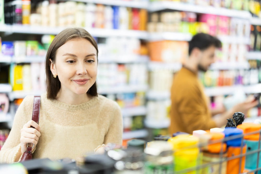 Young woman choosing body and hair care products in supermarket