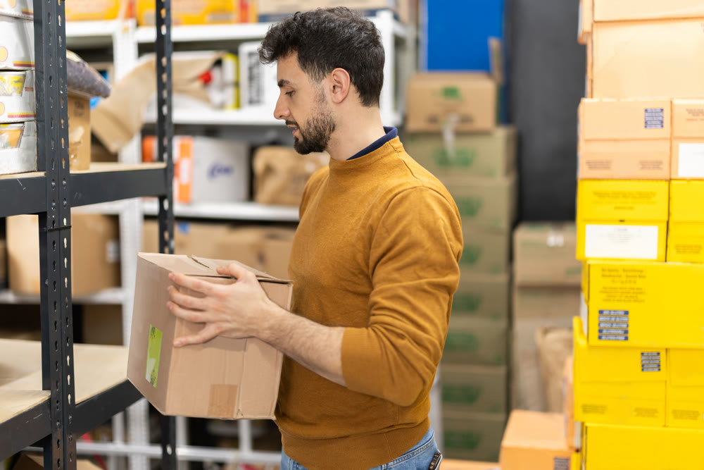 Young man placing package in grocery warehouse