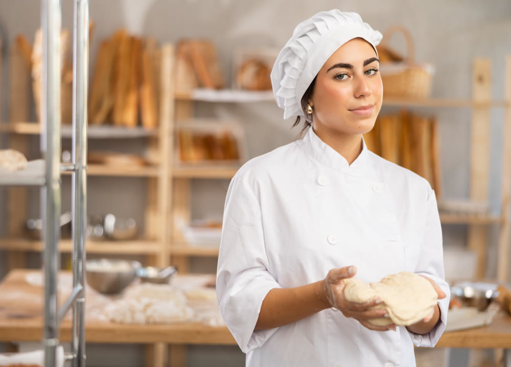 Young female baker with raw dough