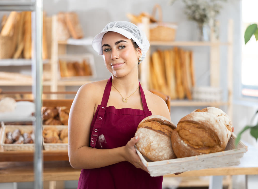 Young saleswoman displays bread in square wicker basket