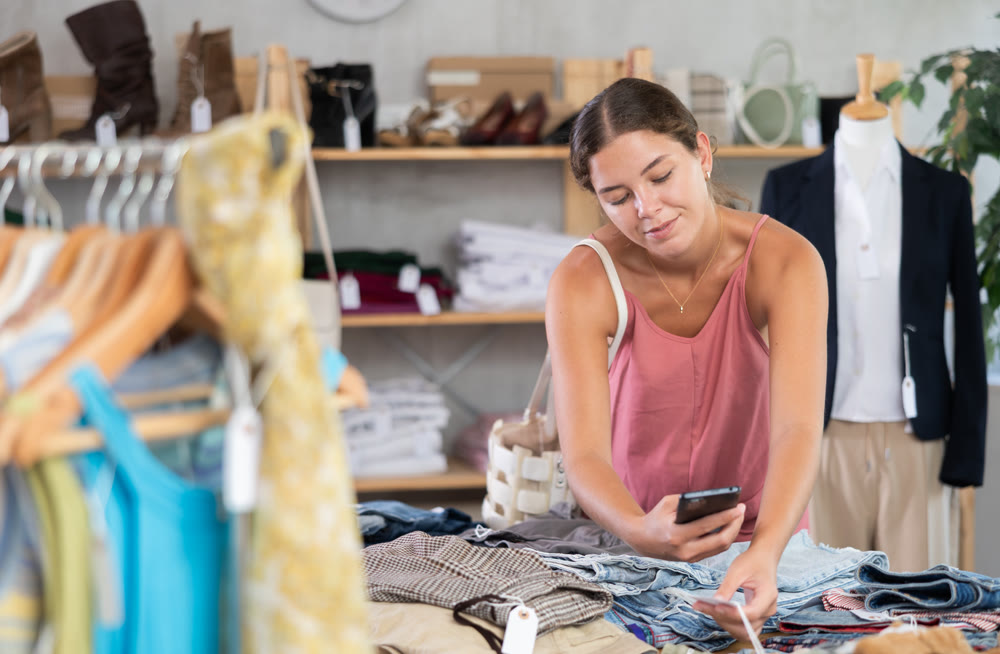 Young woman scanning qr code of trousers in clothing store